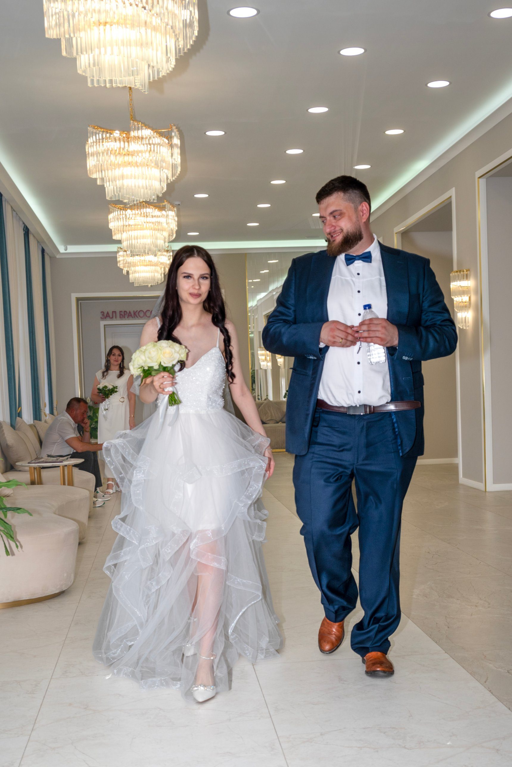 Свадебная фотосъёмка в ЗАГСе: невеста и жених идут по залу